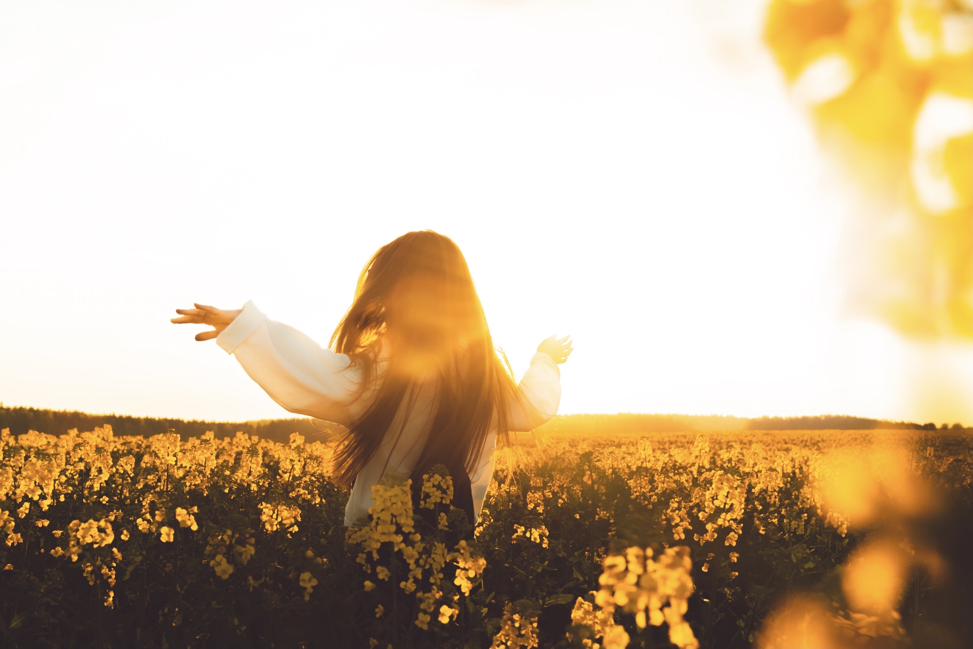 Happy free woman dancing in raps field at golden hour